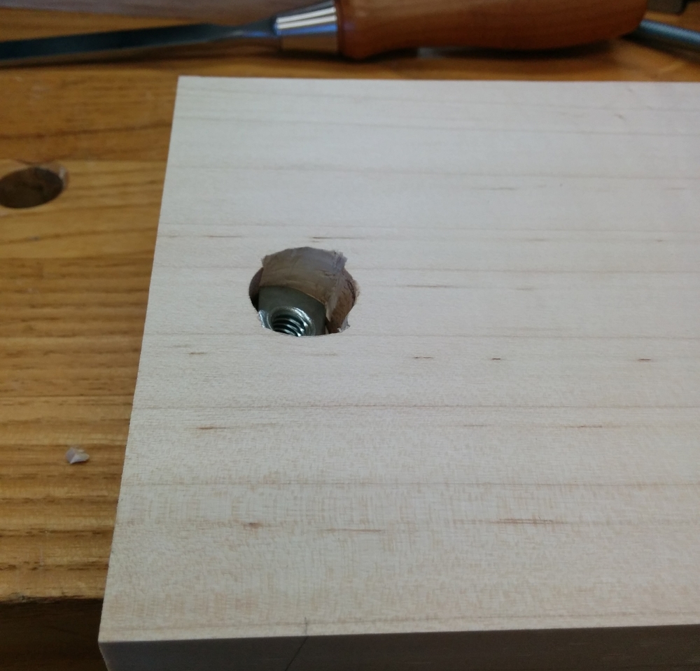  Here you can see the detail of the sliding T-nut installation. The holes are drilled 13 degrees from vertical so that the adjuster is perpendicular to the support block when it is level. I drilled three holes to install this: 1st=diameter of acorn nut and deep enough so that it can recede into the board, 2nd diameter of the barrel of the t-nut and deep enough for the whole barrel, 3rd the 5/16